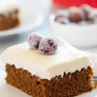 Slice of Gingerbread Cake with Brown Sugar Cream Cheese Frosting, topped with sugared cranberries.