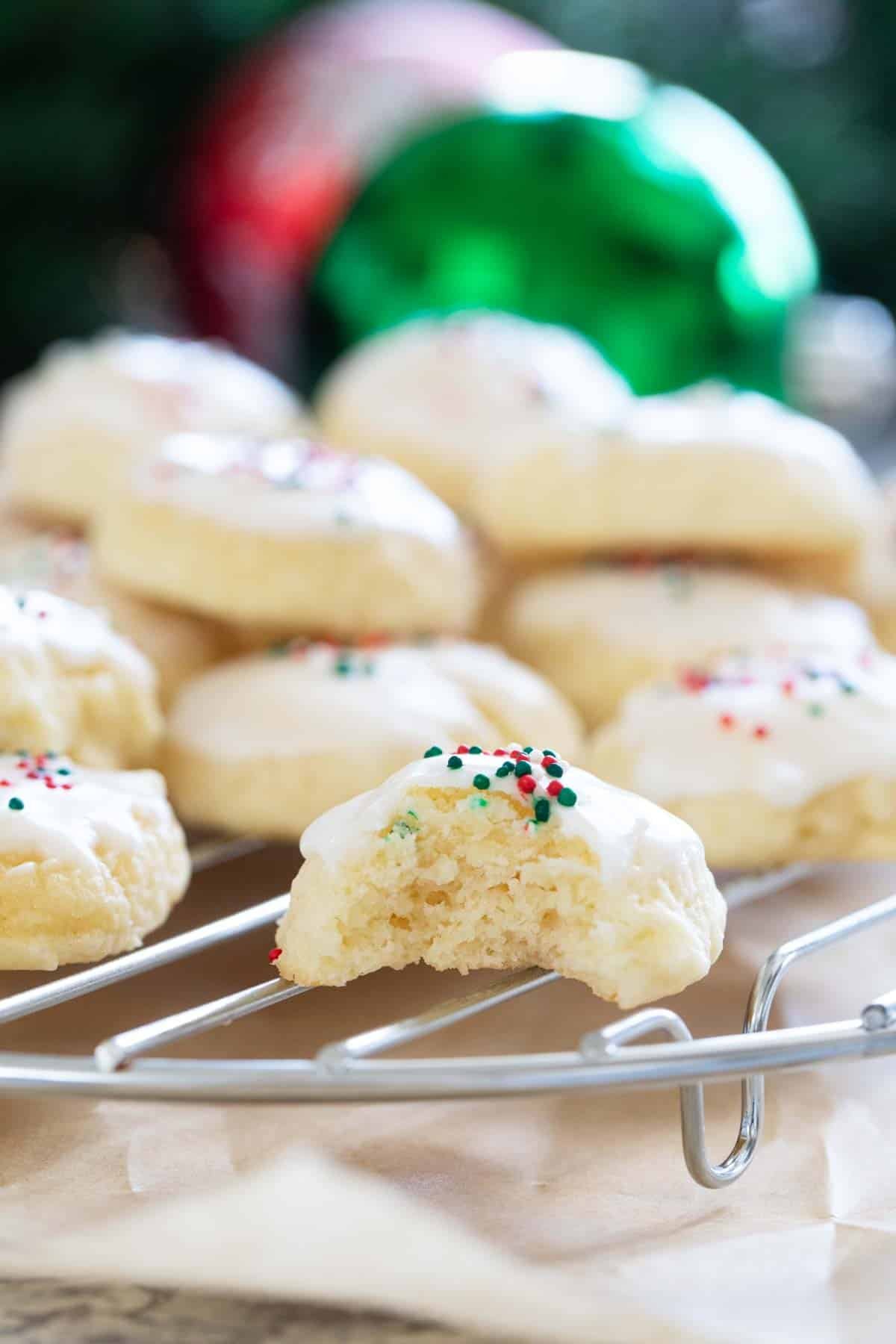 Italian Christmas cookies on a cooling rack, with a bite taken from one cookie.