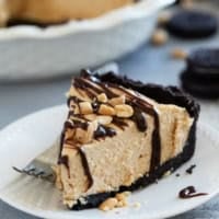 Slice of Peanut Butter Pie on a plate, topped with hot fudge sauce and peanuts.