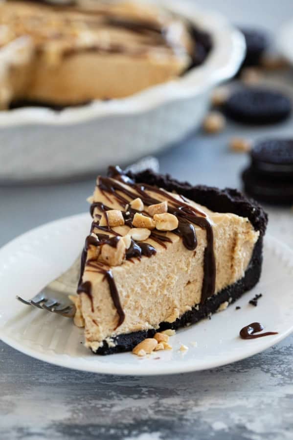Slice of Peanut Butter Pie on a plate, topped with hot fudge sauce and peanuts.