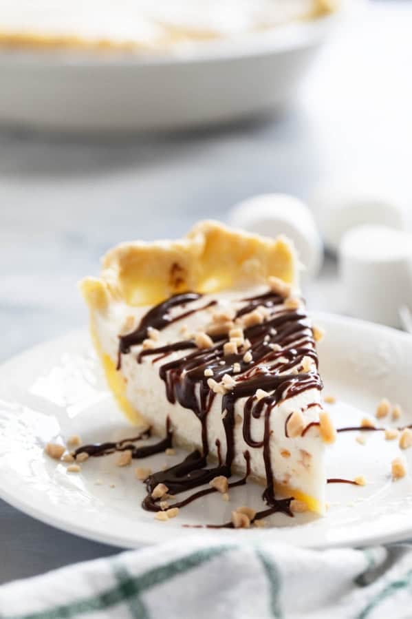 Slice of Toffee Marshmallow Pie with hot fudge drizzled over the top, and sprinkled with toffee pieces.