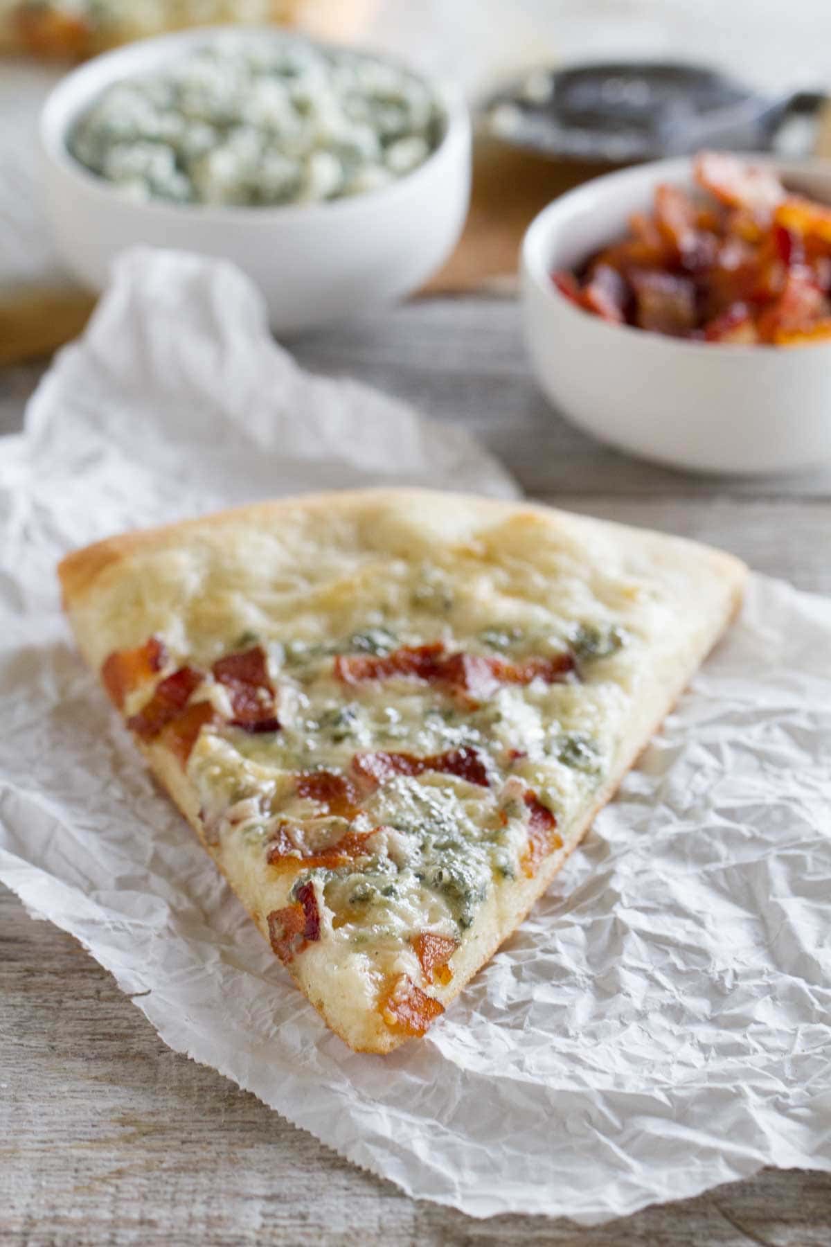 Slice of Blue Cheese and Bacon Pizza on parchment.