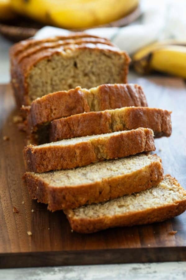 Loaf of buttermilk banana bread on a cutting board, cut into slices.