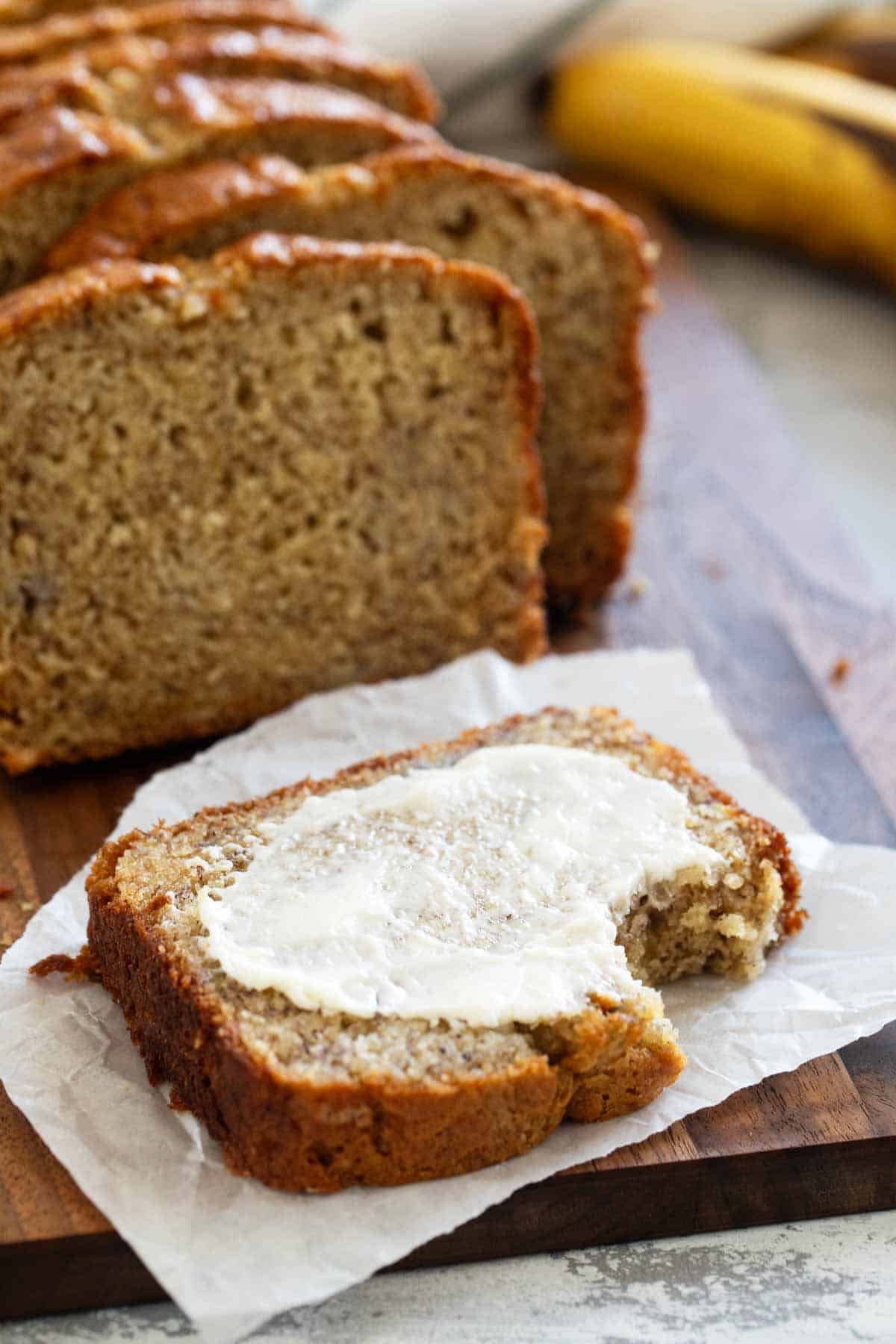 Slice of buttermilk banana bread with butter with a bite taken from it.