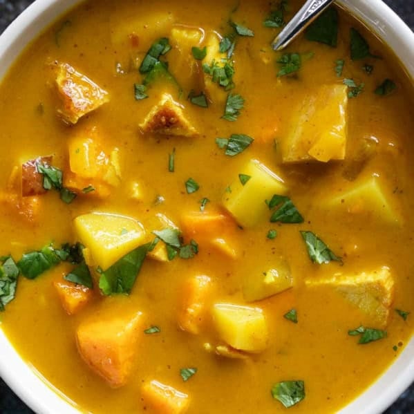 Bowl of chicken curry soup with white and sweet potatoes.