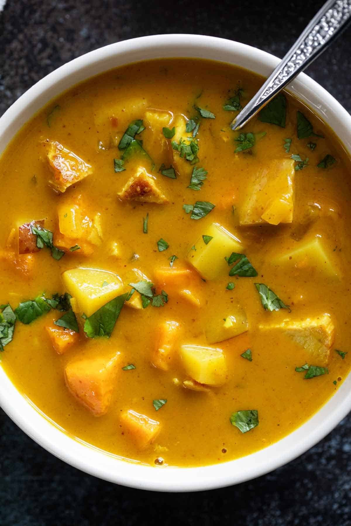 Bowl of chicken curry soup with white and sweet potatoes.