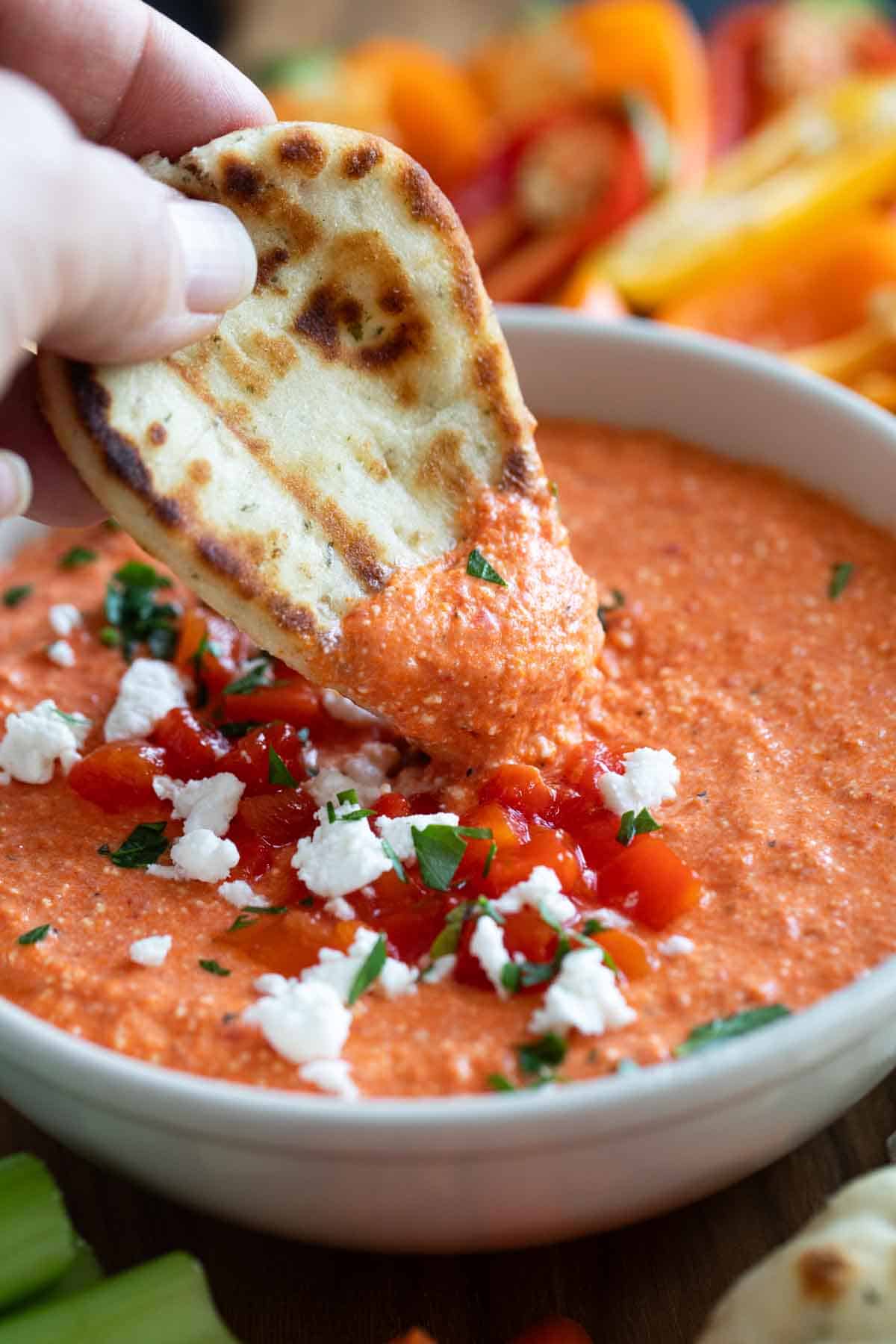 Dipping naan into feta and roasted red pepper dip (htipiti).