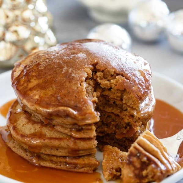 Stack of gingerbread pancakes with a bite taken from them.