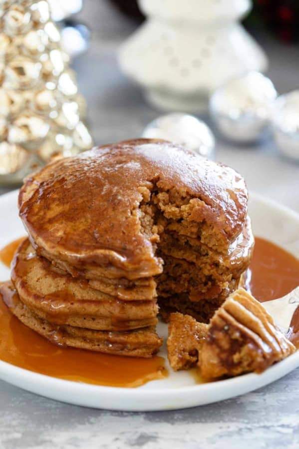 Stack of gingerbread pancakes with a bite taken from them.