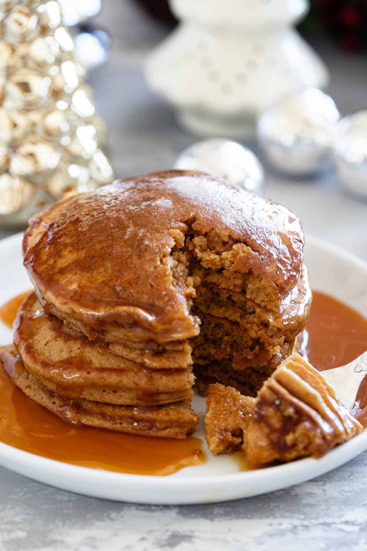 Stack of gingerbread pancakes with a bite taken from them.