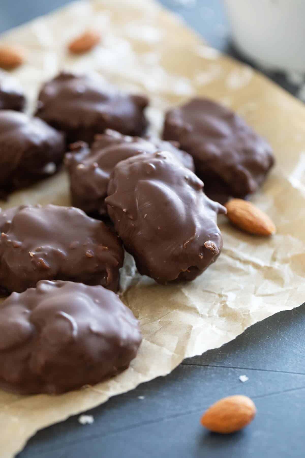 Homemade Almond Joys stacked on a piece of parchment paper.