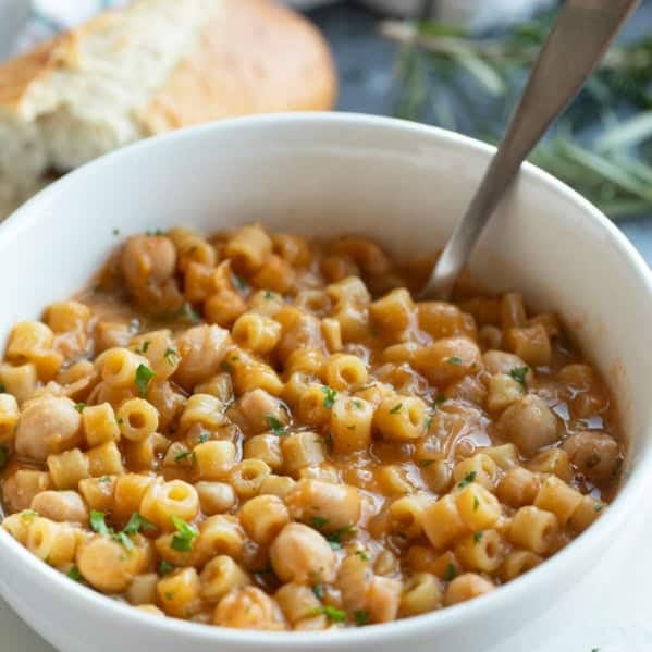 Bowl filled with Pasta with Chickpeas (Pasta e Ceci) topped with parsley and rosemary.