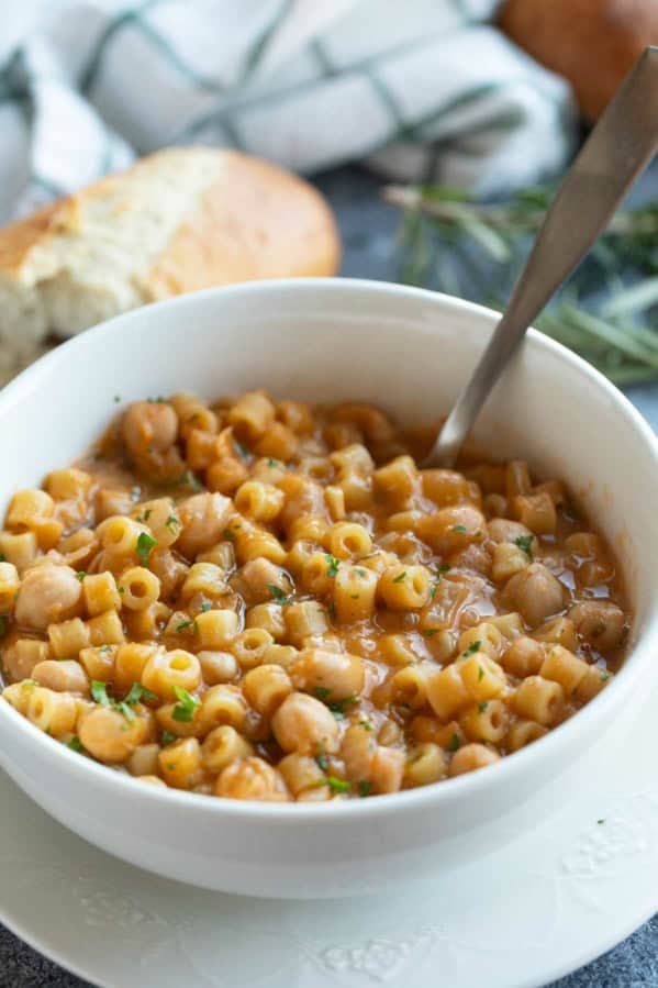 Bowl filled with Pasta with Chickpeas (Pasta e Ceci) topped with parsley and rosemary.
