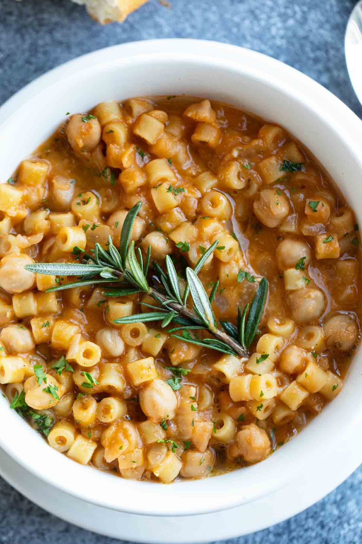 Bowl of pasta with chickpeas (pasta e ceci) topped with fresh rosemary.