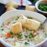 Bowl of Chicken Pot Pie Soup with peas, carrots, and potatoes, topped with puff pastry squares.