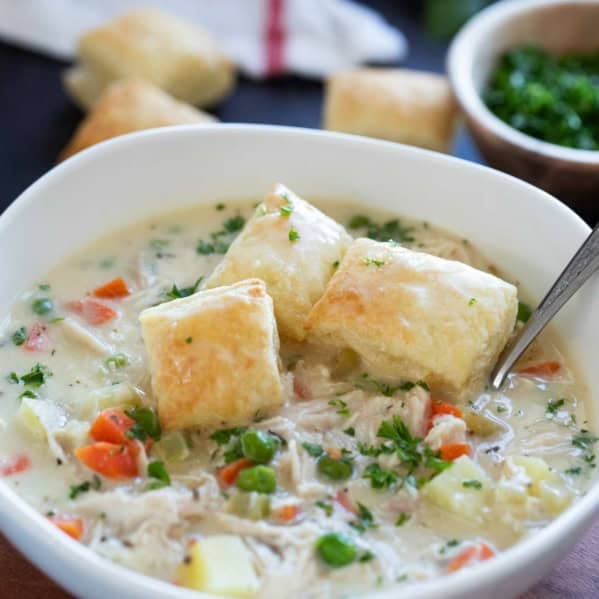 Bowl of Chicken Pot Pie Soup with peas, carrots, and potatoes, topped with puff pastry squares.