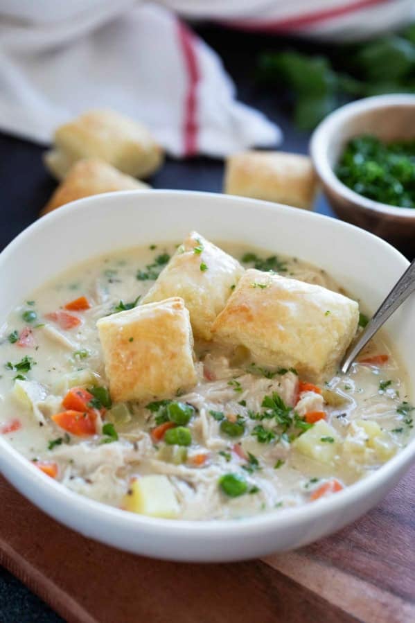 Bowl of Chicken Pot Pie Soup with peas, carrots, and potatoes, topped with puff pastry squares.