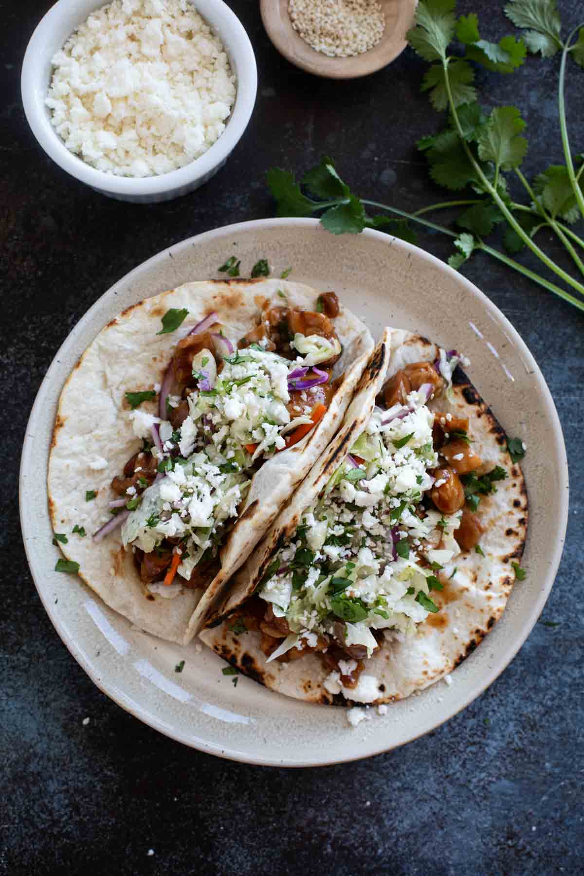 Two honey garlic chicken tacos on a plate.