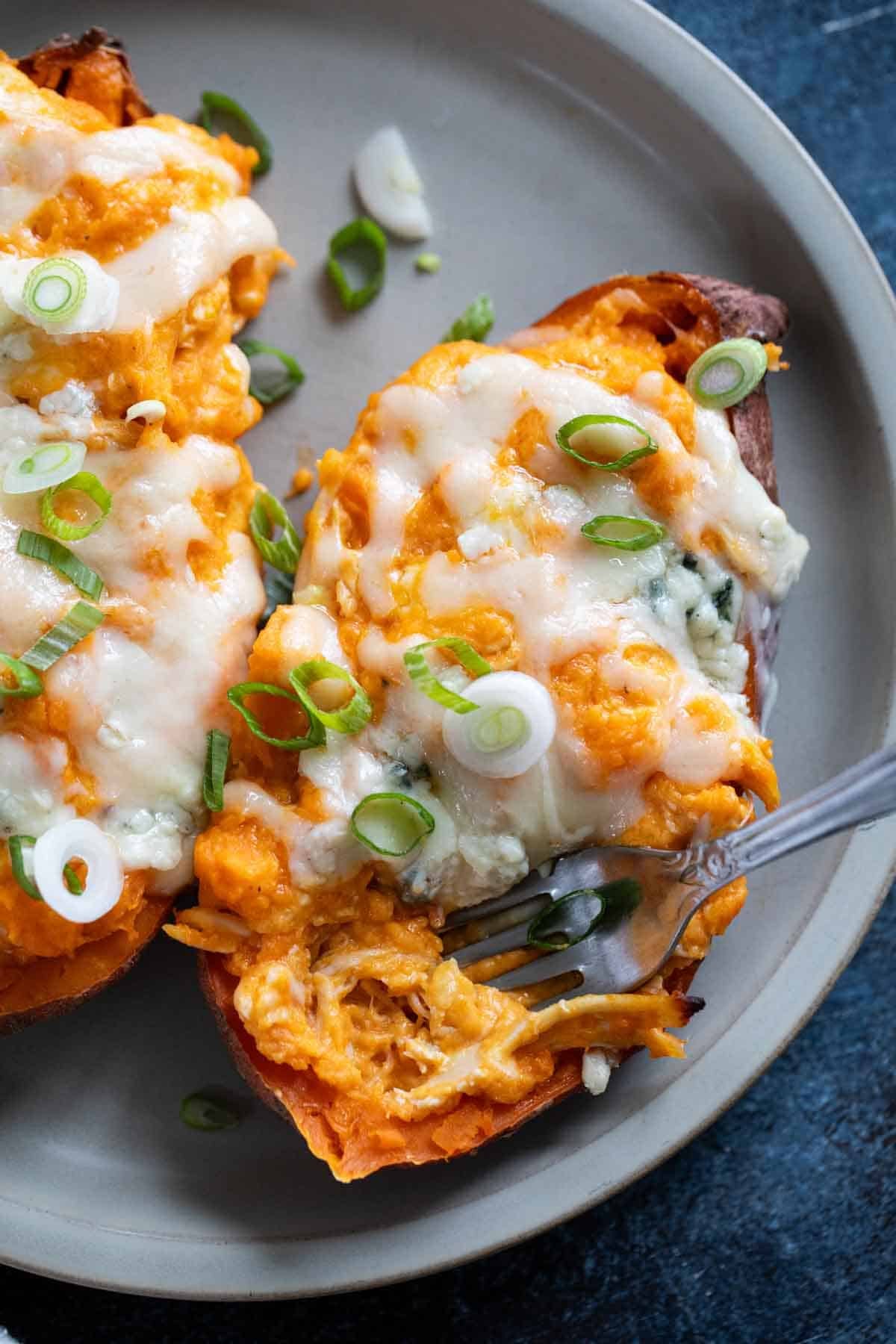 Twice Baked Buffalo Chicken Sweet Potatoes with a fork in one half of the potato.