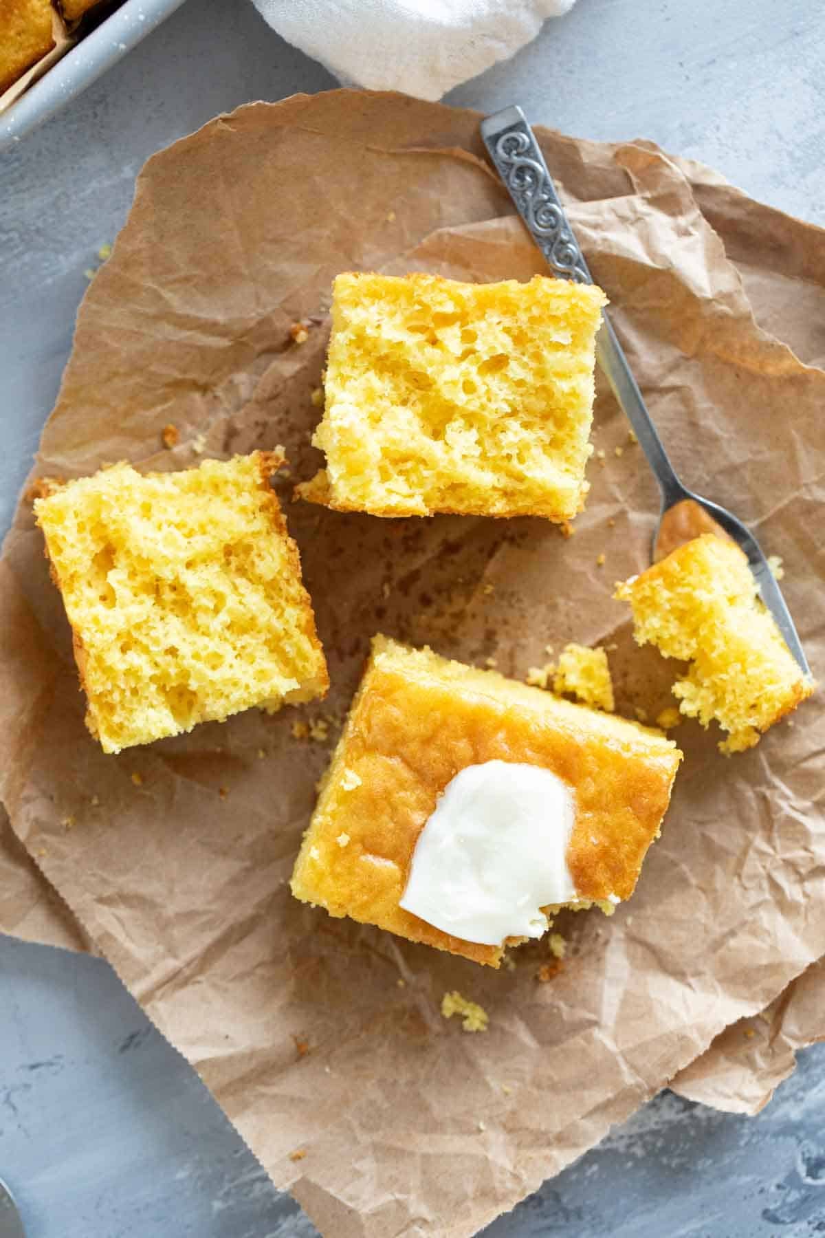 Pieces of Boston Market Cornbread cut in half and topped with butter.