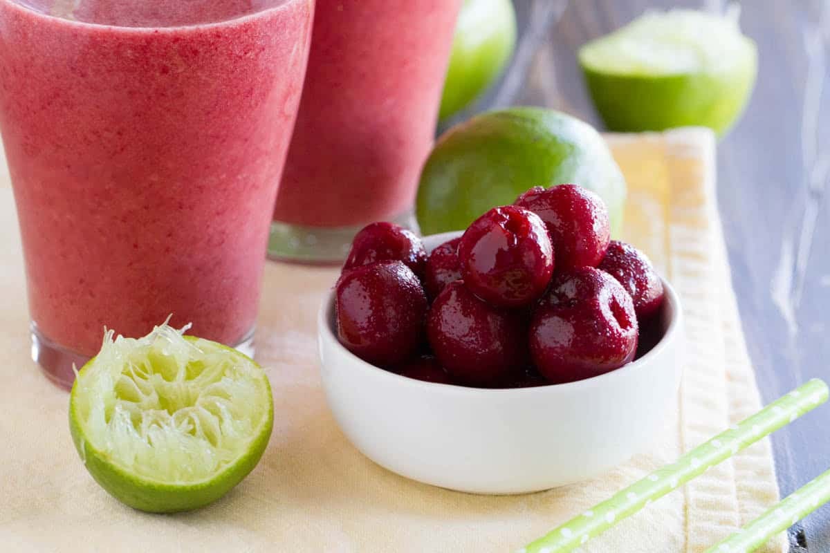 Frozen cherries in a cup, and a juiced lime.