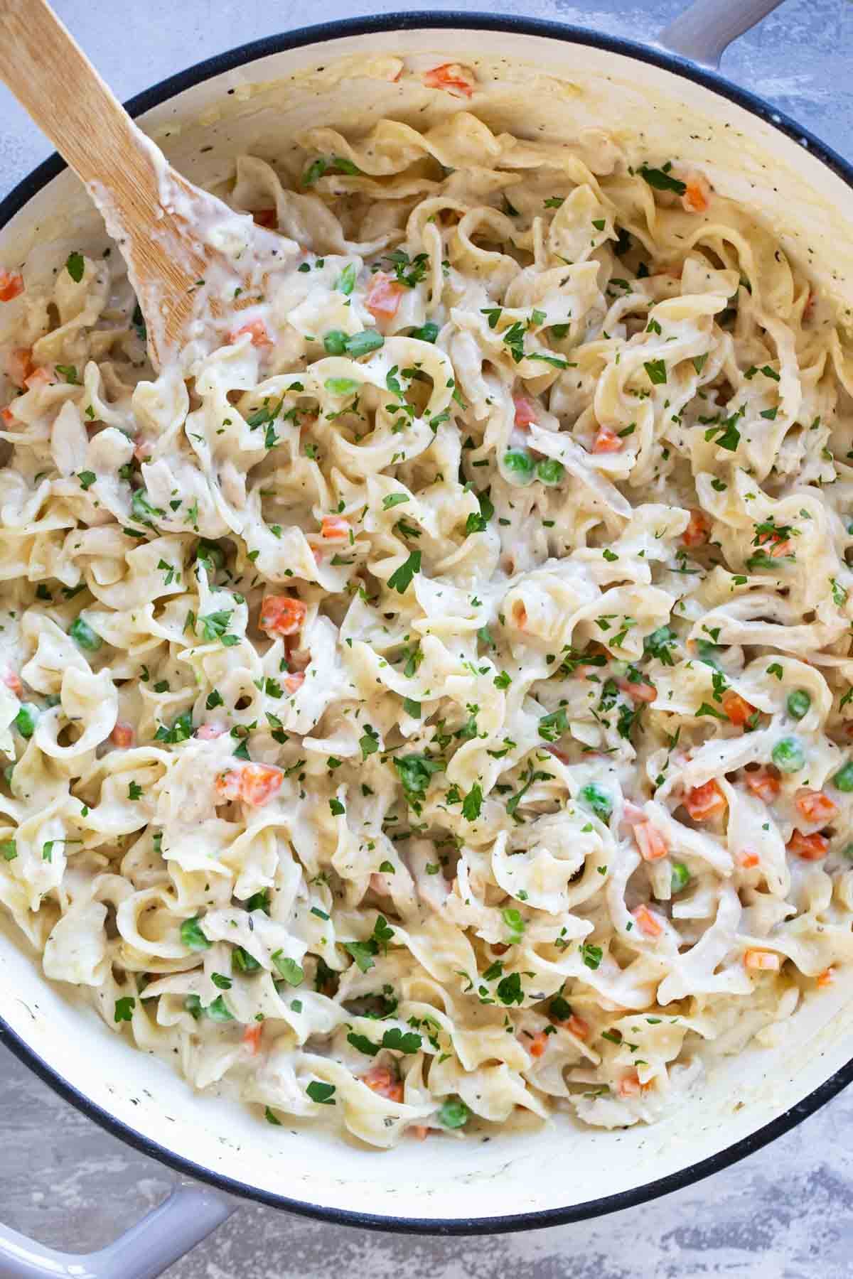 Chicken Pot Pie Pasta in a skillet with a wooden spoon.
