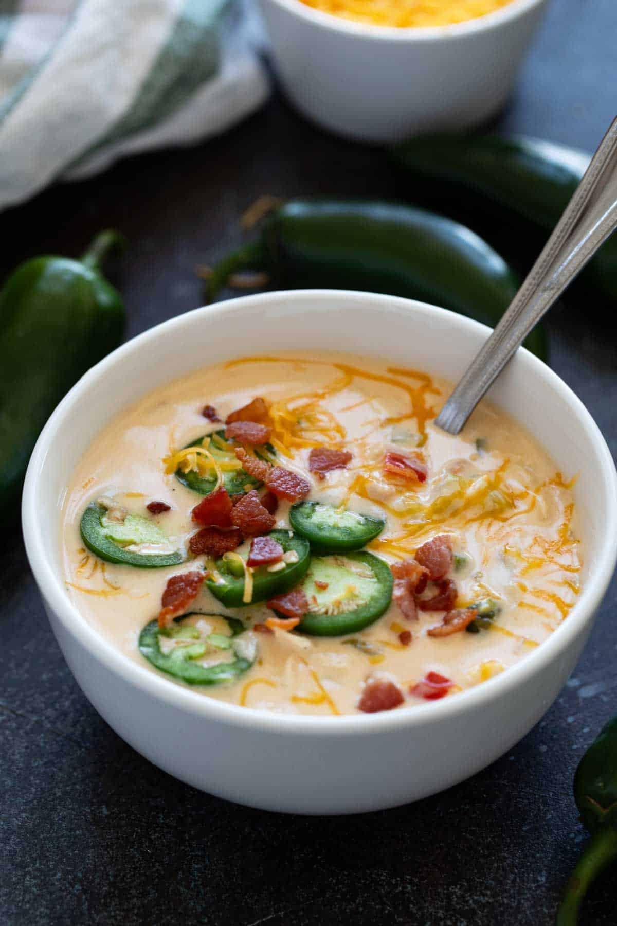Bowl of Jalapeno Popper Soup topped with cheese, bacon, and jalapeno slices.