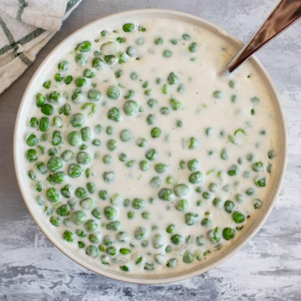 Serving bowl filled with Creamed Peas.