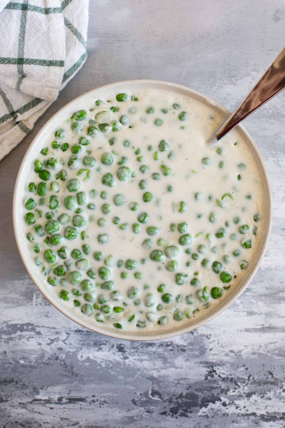 Serving bowl filled with Creamed Peas.