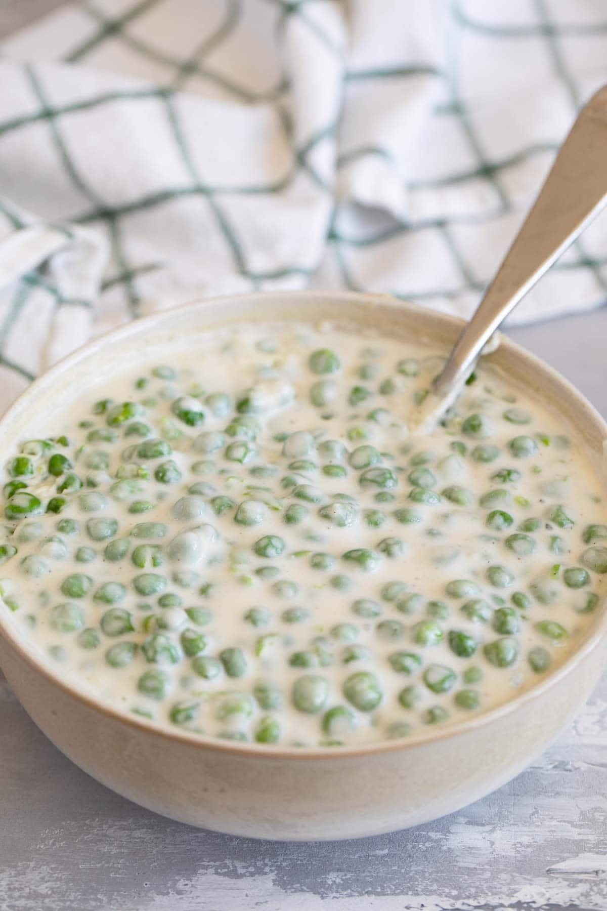 Bowl of creamed peas with a spoon.