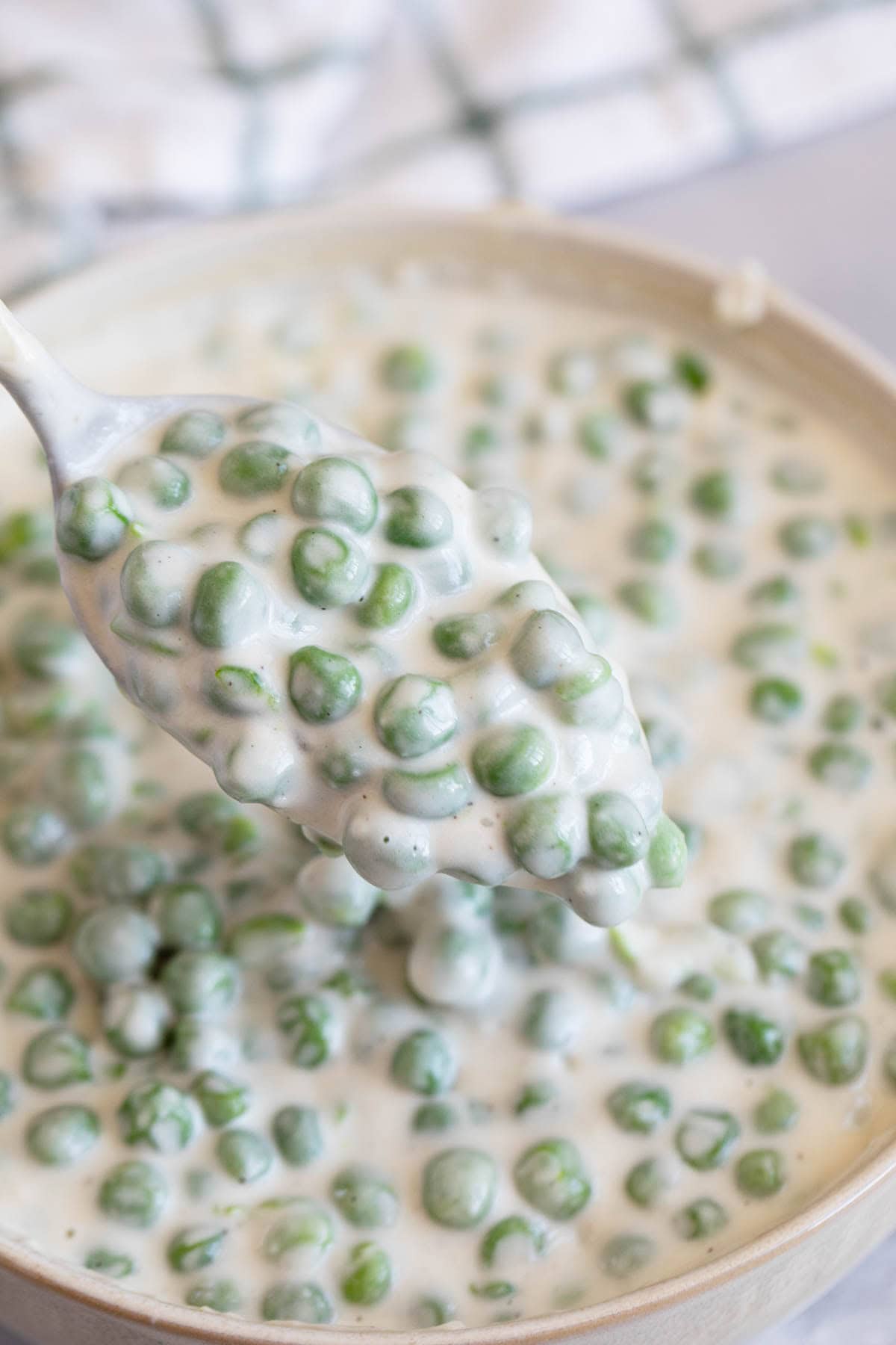 Spoonful of Creamed Peas over a bowl.