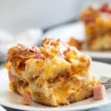 Slice of Croissant Breakfast Casserole with ham and cheese on a plate.