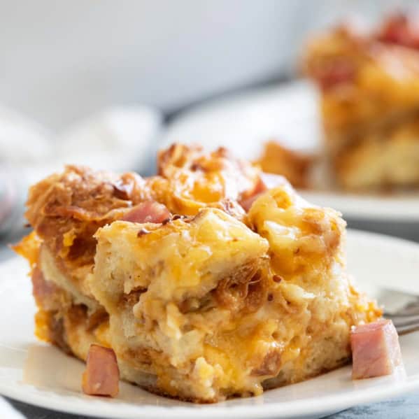 Slice of Croissant Breakfast Casserole with ham and cheese on a plate.