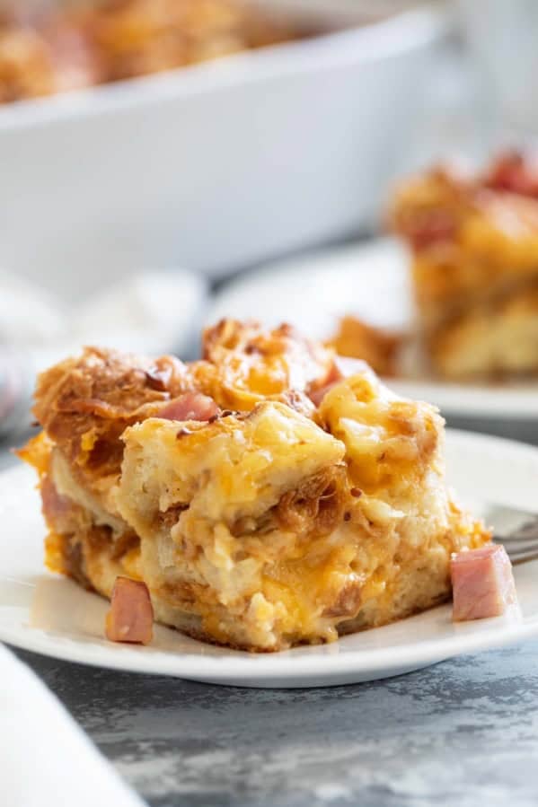 Slice of Croissant Breakfast Casserole with ham and cheese on a plate.