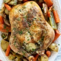 Garlic Roast Chicken over roasted vegetables on a serving tray.