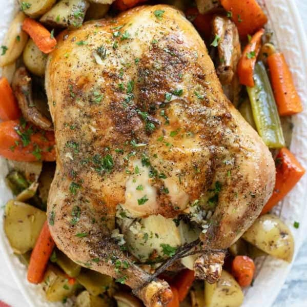 Garlic Roast Chicken over roasted vegetables on a serving tray.