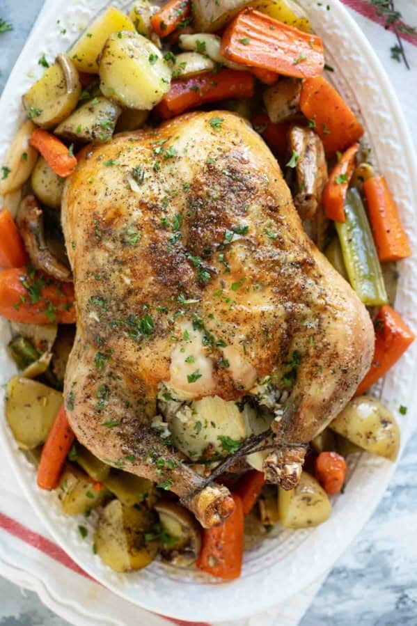 Garlic Roast Chicken over roasted vegetables on a serving tray.