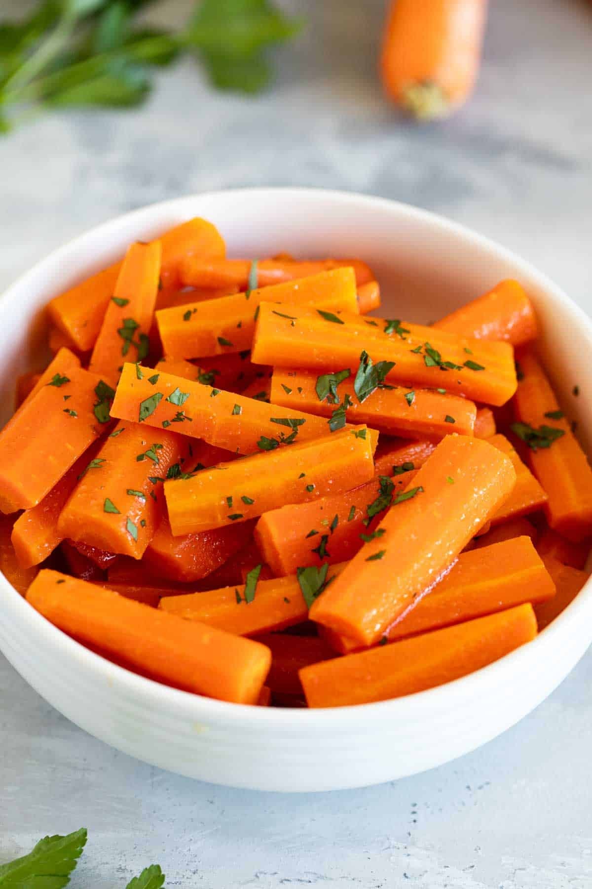 Bowl of slow cooker carrots topped with minced parsley.