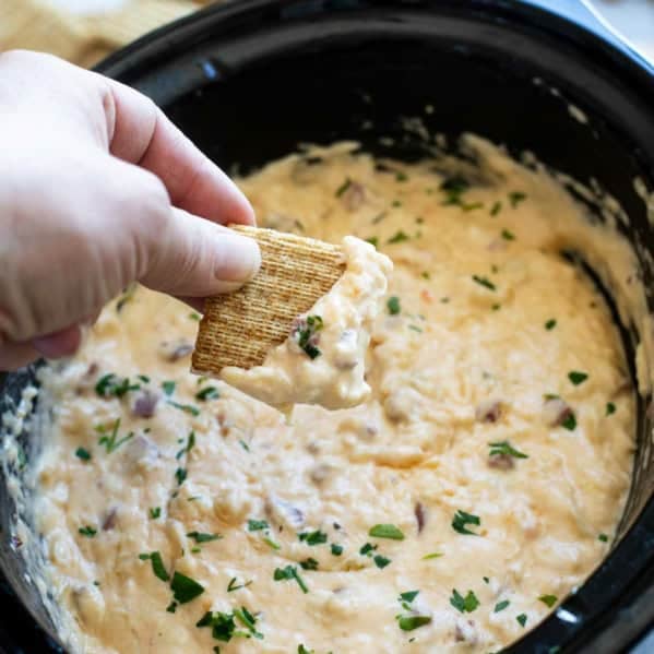 Dipping a cracker into Slow Cooker Reuben Dip.