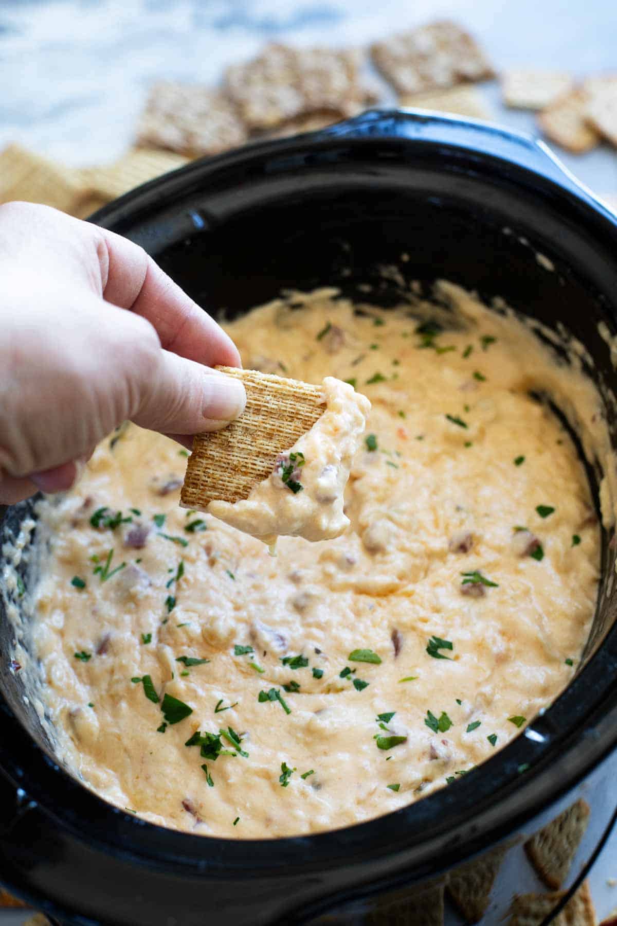 Dipping a cracker into Slow Cooker Reuben Dip.