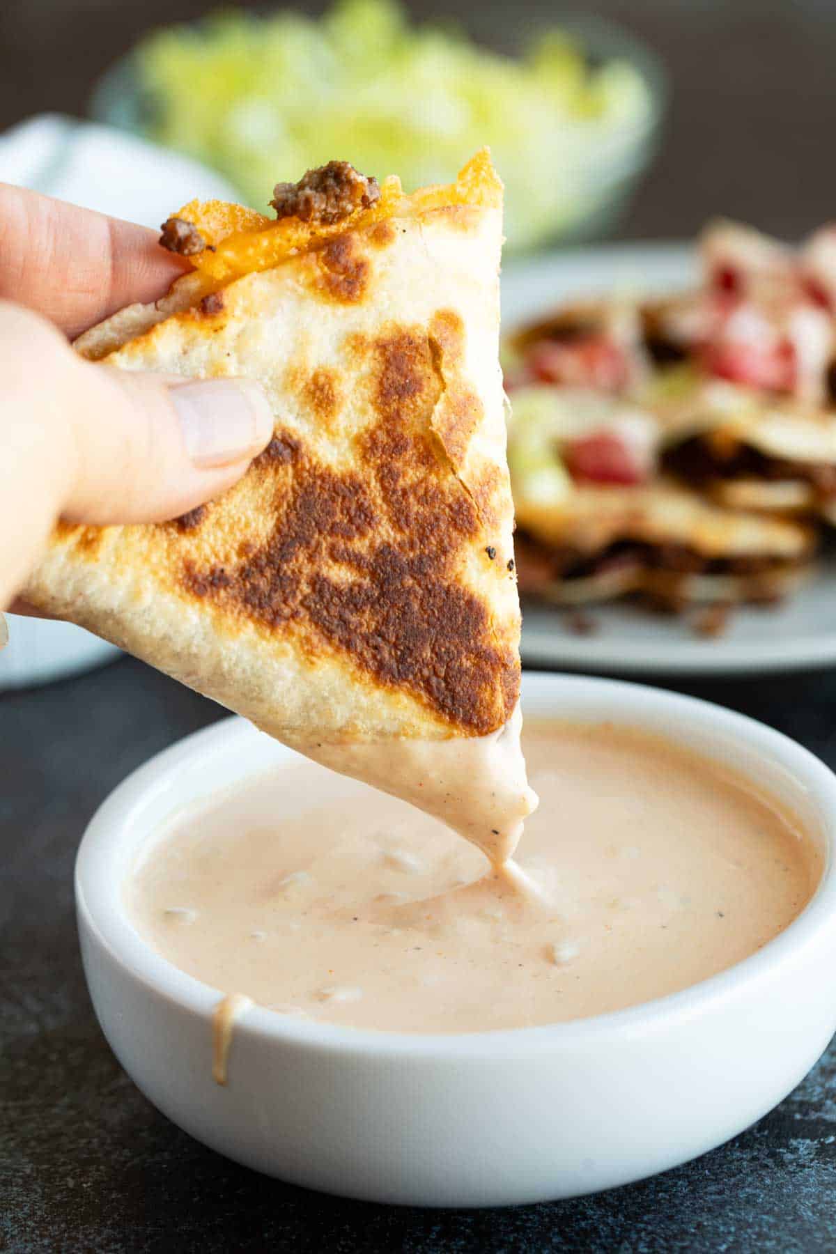 Dipping a bacon cheeseburger quesadilla into special sauce.