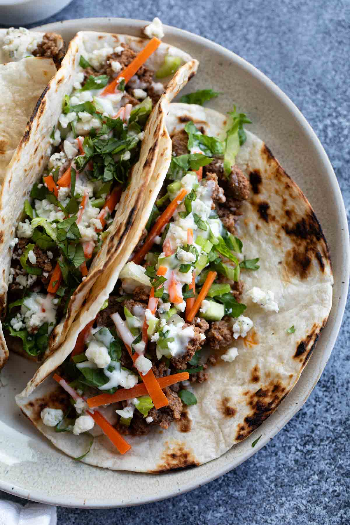 Buffalo Beef Tacos on a plate topped with celery and carrots.