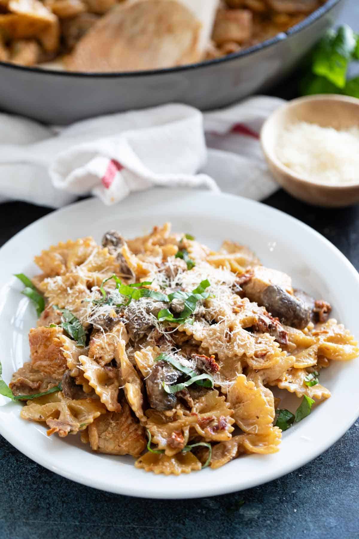 Serving of Chicken Pasta Milano on a plate, topped with parmesan cheese.