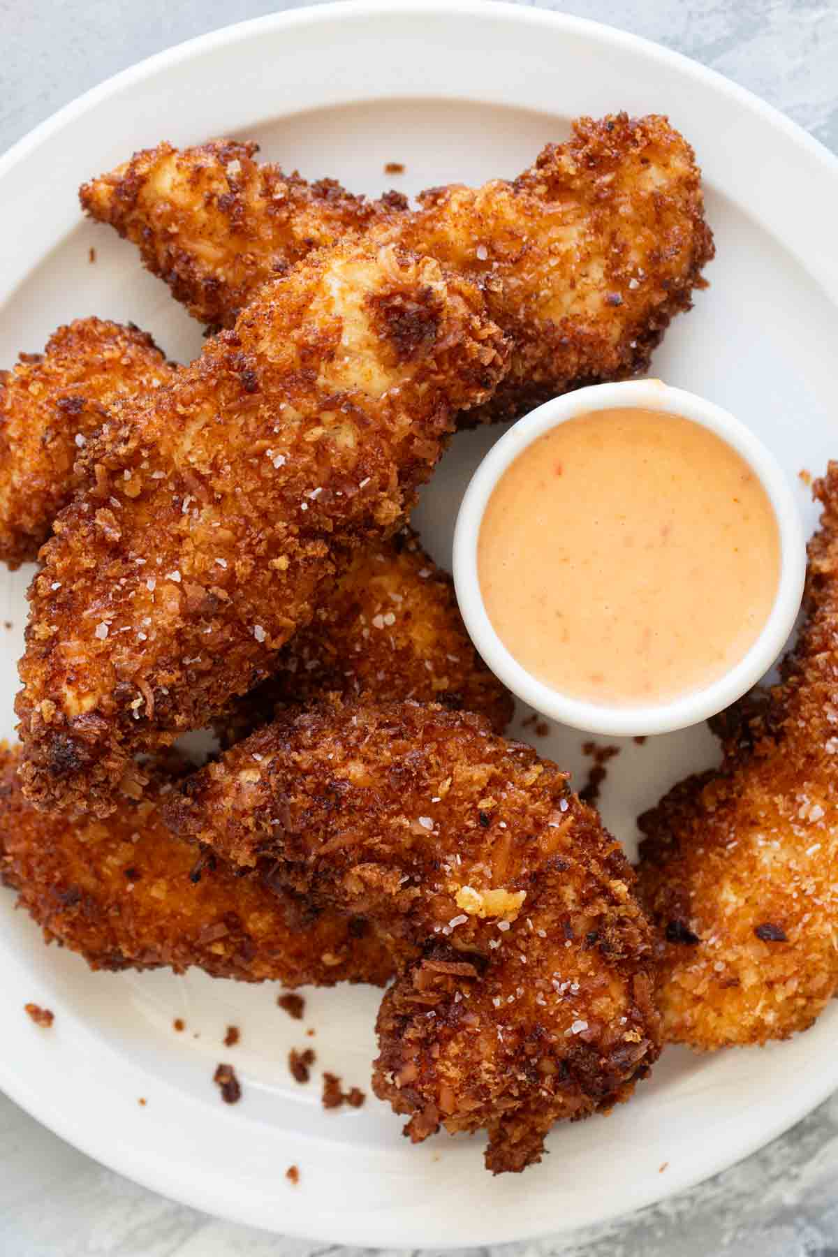 Plate filled with coconut chicken tenders and spicy mayonnaise.