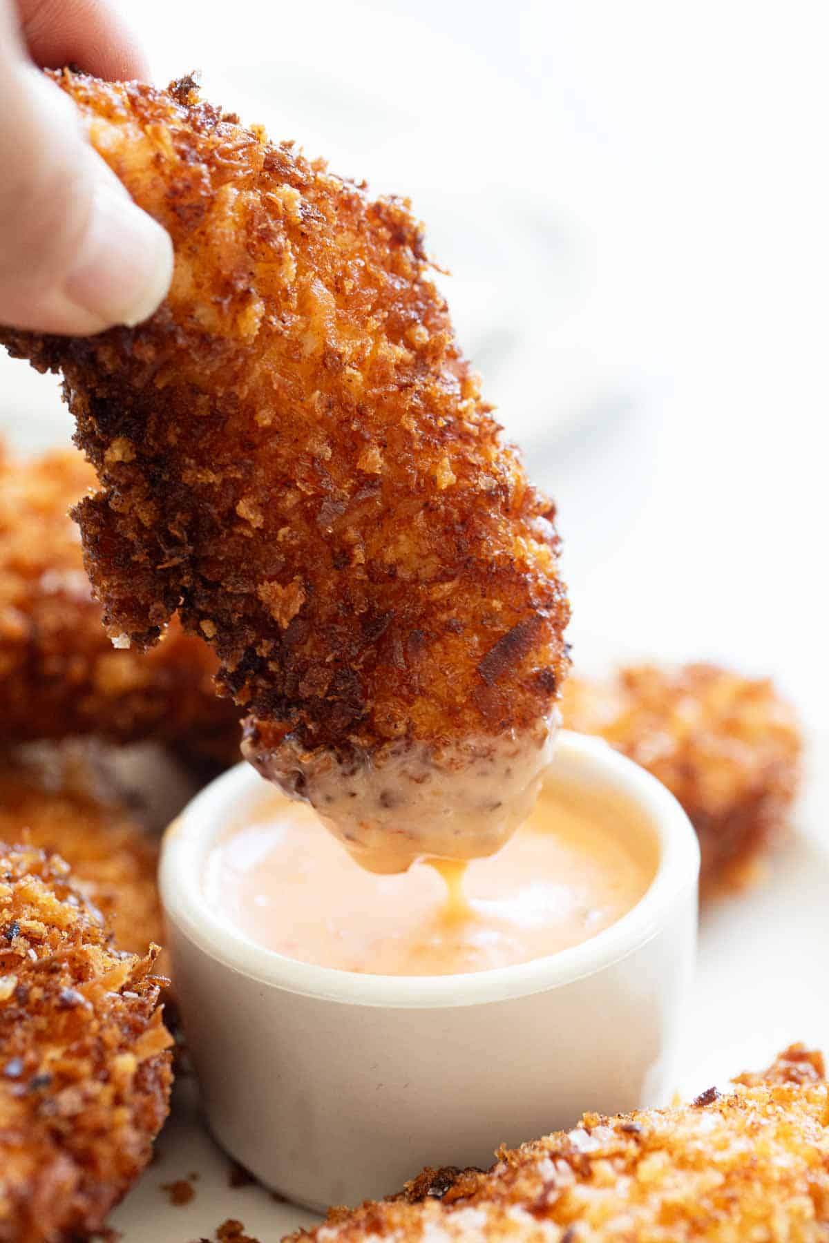 Dipping a coconut chicken tender into spicy mayonnaise.