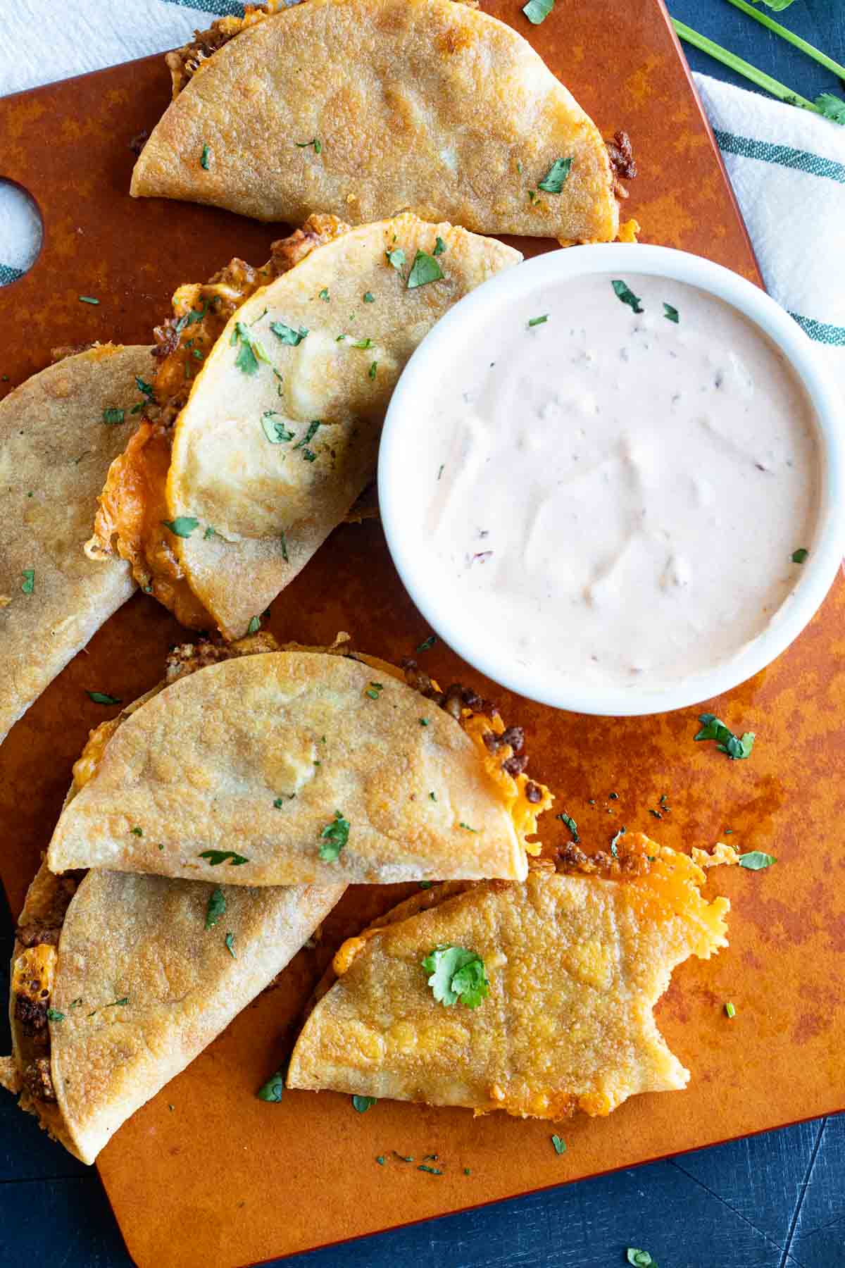Crispy Chicken Tacos on a cutting board with a bite taken from one taco.
