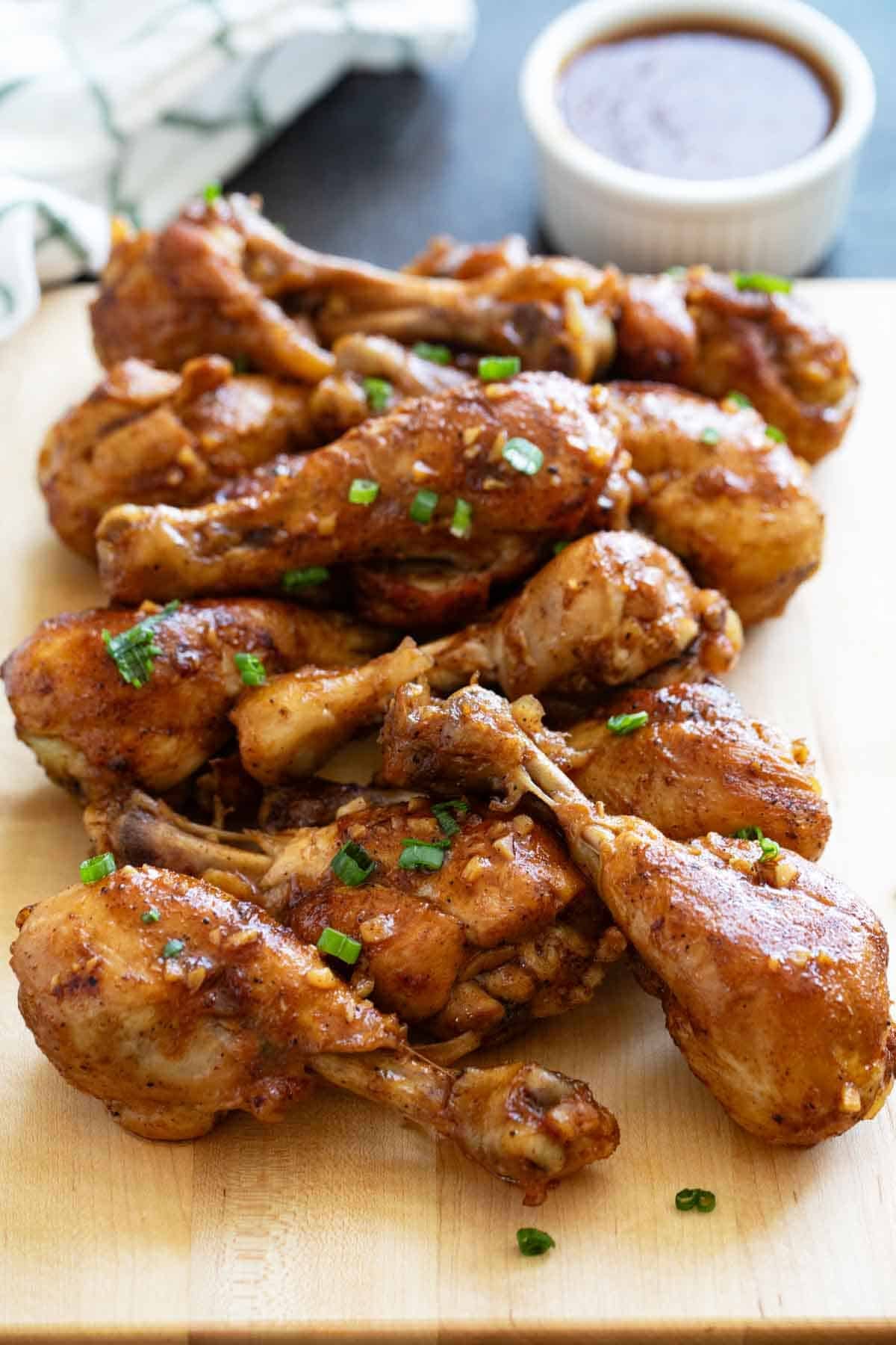 Honey Balsamic Chicken Drumsticks stacked on a cutting board.