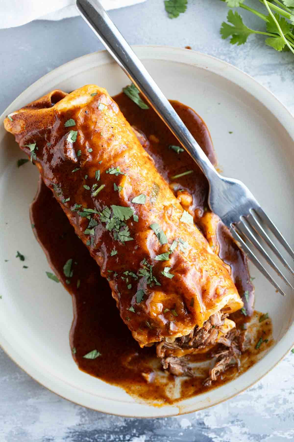 Slow Cooker Chile Colorado Burrito on a plate with a bite taken from one end.