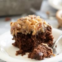 Slice of German Chocolate Cake on a plate with a fork full of cake on the side.