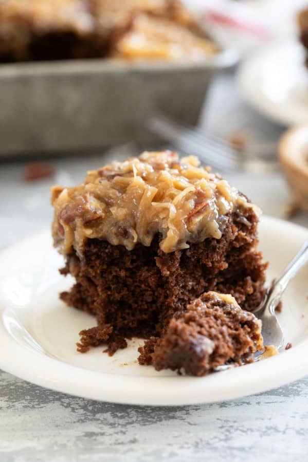 Slice of German Chocolate Cake on a plate with a fork full of cake on the side.